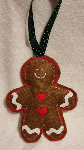 Felt gingerbread man ornament with a red heart on a beige background